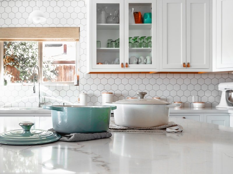 Calacatta-veined quartz kitchen island with cast-iron pots and a hexagonal tile backsplash